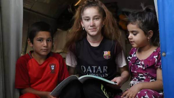 Participant Nadia reads to her siblings at their home in a displacement camp in Iraq.