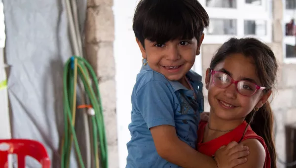 Participant Soleen carries her younger brother in their home.