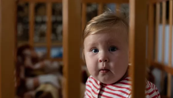 A child from Ukraine sitting in a cot. 