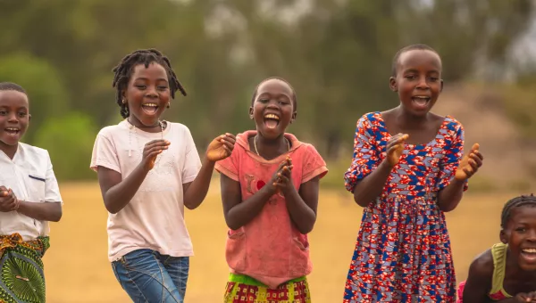 Four young girls in Uganda laughing and clapping