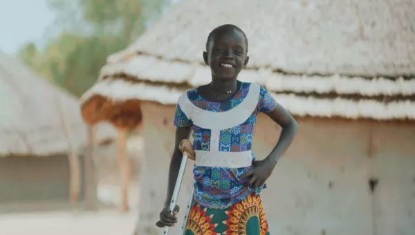 Adit standing near her home and smiling. 