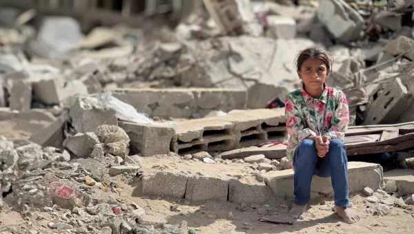 Girl sitting on the rubble from a collapsed building. 