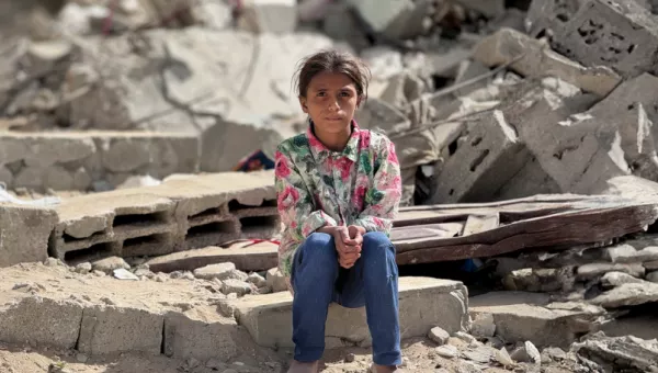 Girl sitting on the rubble from a collapsed building. 