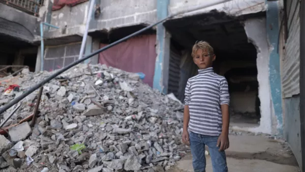 A boy standing next to a collapsed building in Gaza.