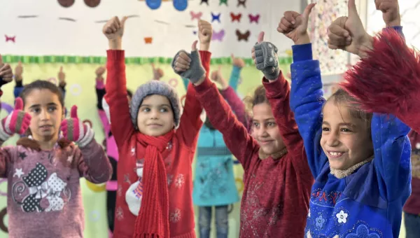 Children smiling and holding thumbs up.