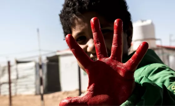 Child with their hand painted red as part of War Child activities to mark Red Hand Day, also known as the International Day against the Use of Child Soldiers.