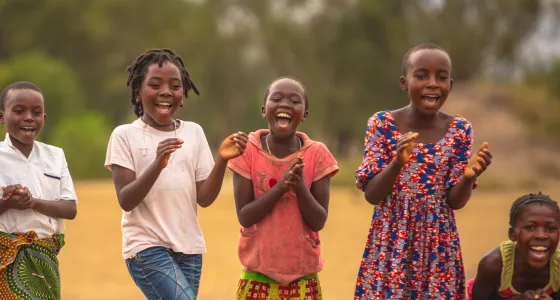 Four young girls in Uganda laughing and clapping