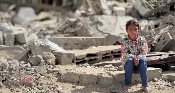 Girl sitting on the rubble from a collapsed building. 