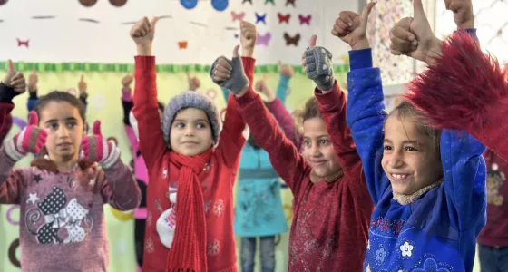 Children smiling and holding thumbs up.