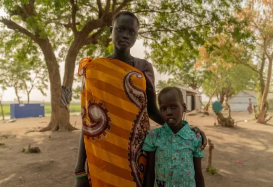 The siblings standing together near their home. 