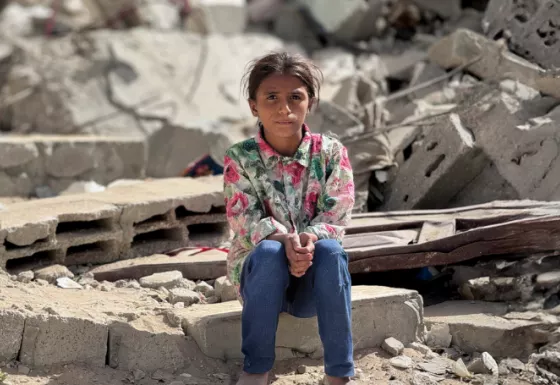 Girl sitting on the rubble from a collapsed building. 