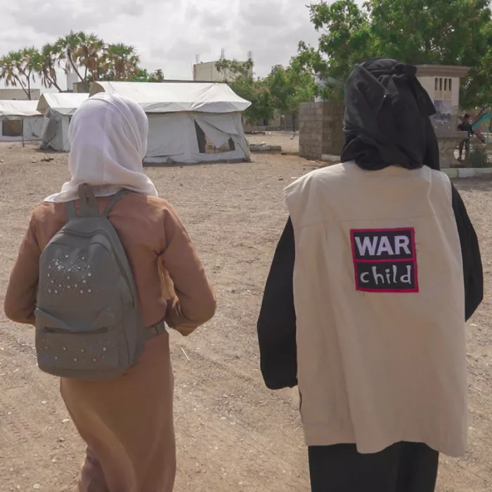 Amina Noor and War Child member of staff walking together.